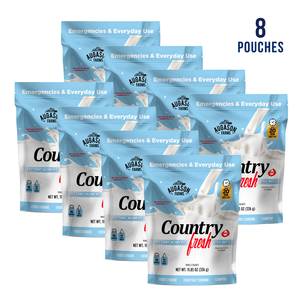 Eight Augason Farms Country Fresh Instant Nonfat Dry Milk Pouches (16 servings each) in blue and white packaging, displayed in two staggered rows. Fortified with vitamins A and D—ideal for emergencies or daily use.
