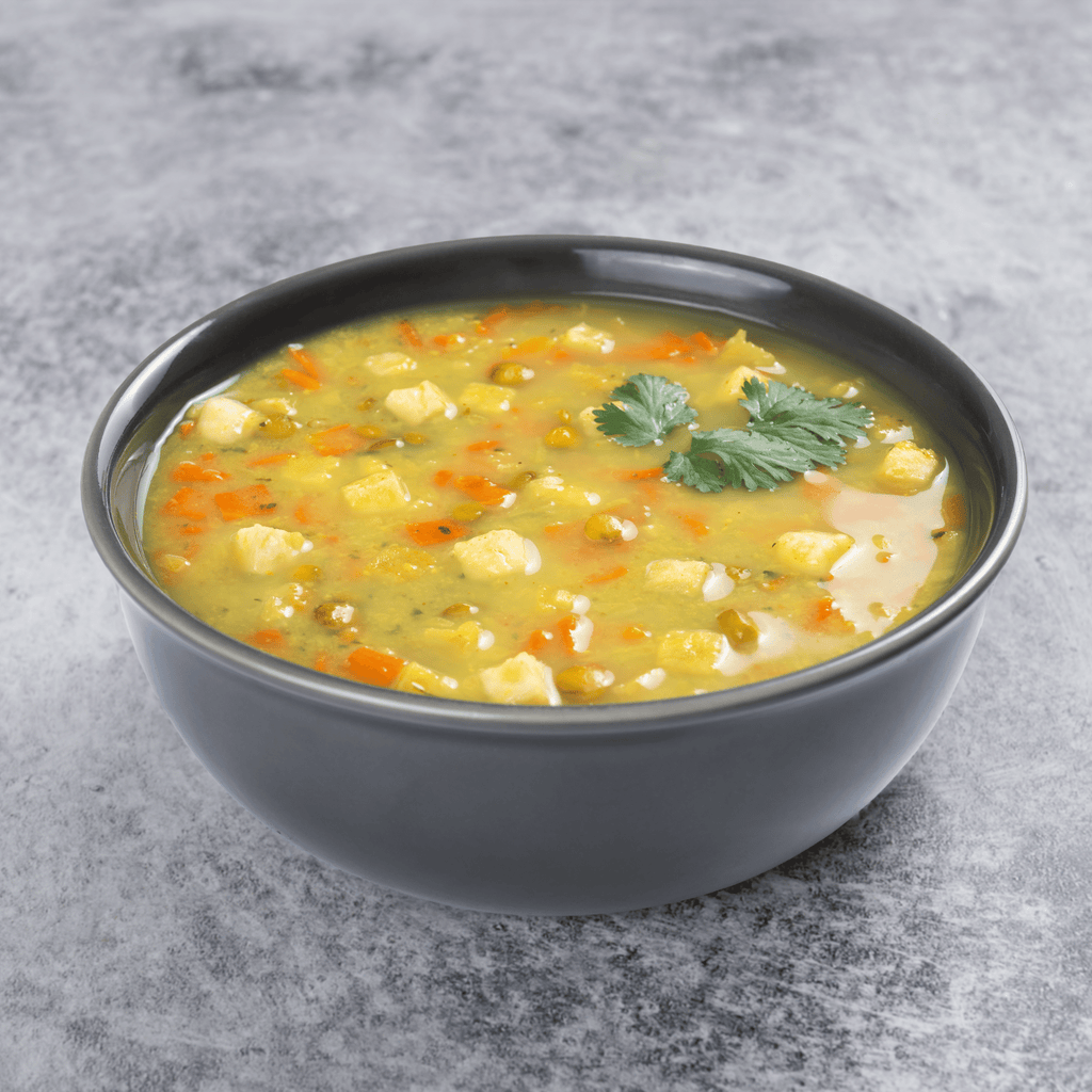 A gray bowl of Augason Farms Soup Pouch Variety Pack (4 flavors, 32 servings) soup, garnished with cilantro, sits on a light gray surface—ideal for quick meals or stocking your emergency food supply.